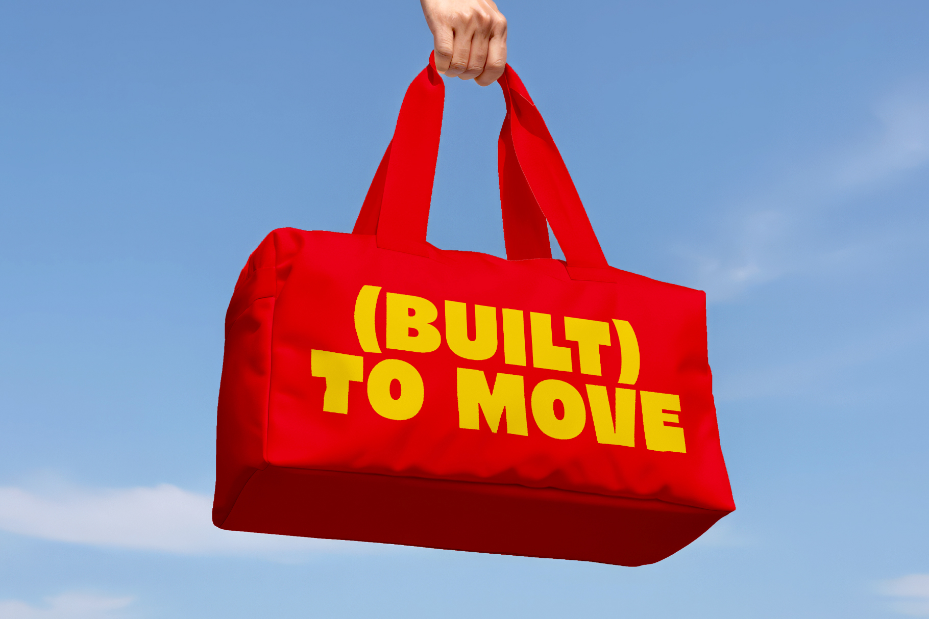 Red canvas tote bag with yellow built to move text against blue sky