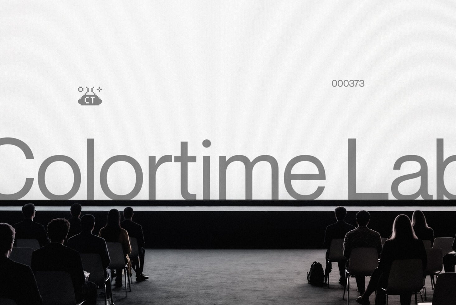Large text on projection screen with audience seated facing it