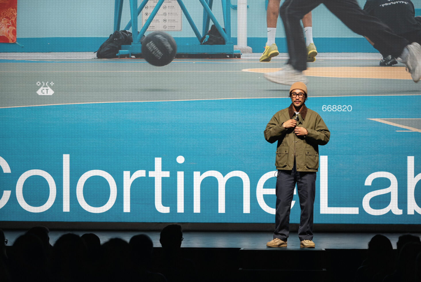 Speaker on stage with gym equipment overlay, colorful gradient backdrop