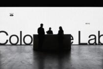 Three silhouetted figures sitting behind black desk with large partial text visible behind them