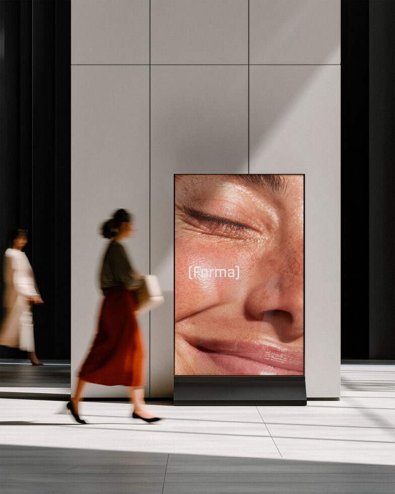 Digital display screen showing close-up skin texture with (forma) text overlay in public space