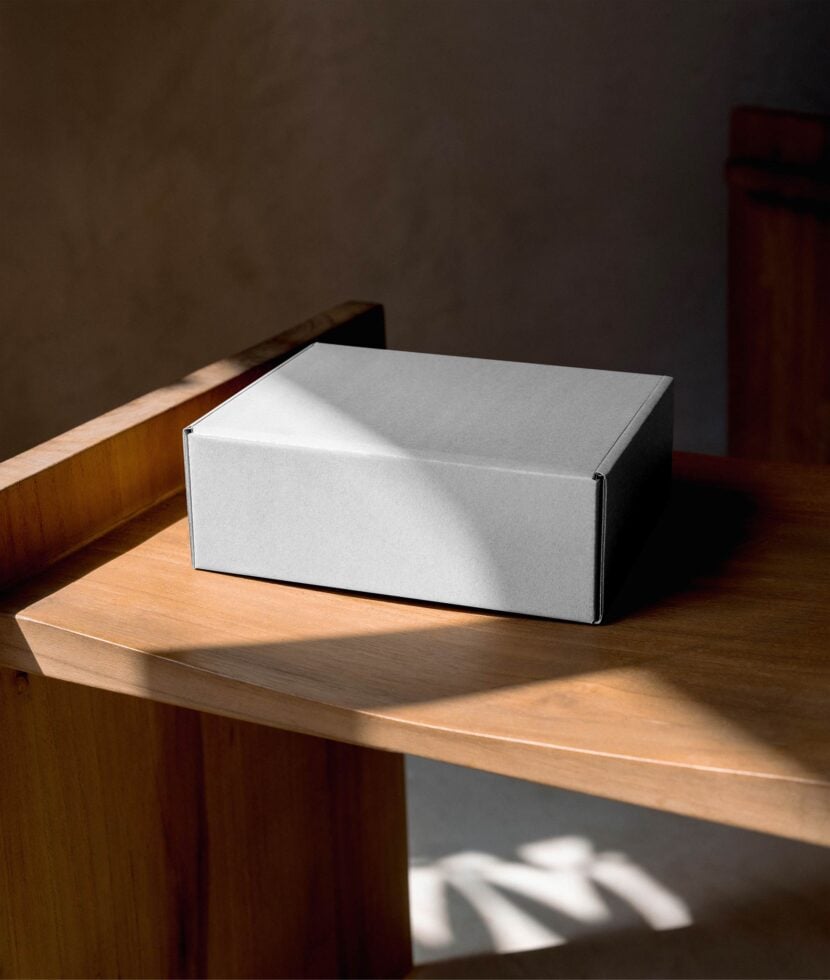 White cardboard box sitting on wooden shelf with natural sunlight streaming across