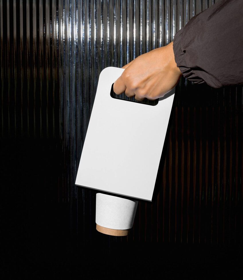 Hand holding blank white clipboard with black handle against corrugated metal backdrop