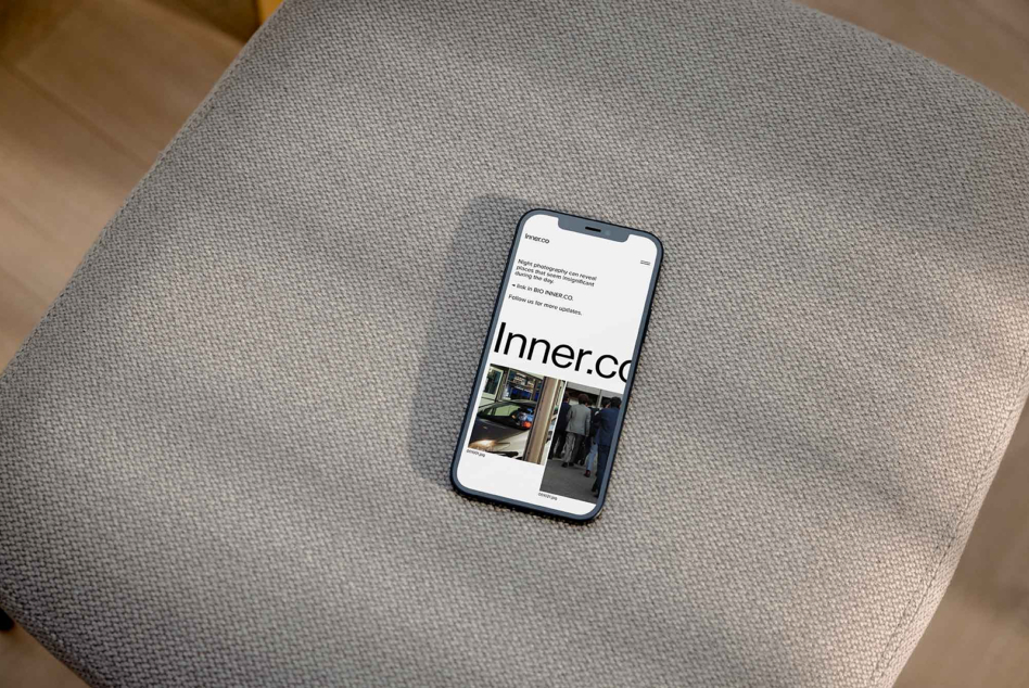 Phone showing website on gray cushion, displaying branding mockup