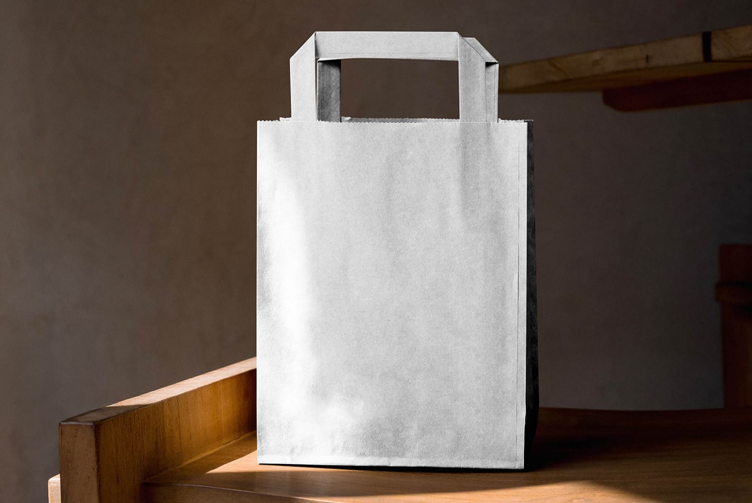 Blank white paper bag with scalloped edge trim on wooden table