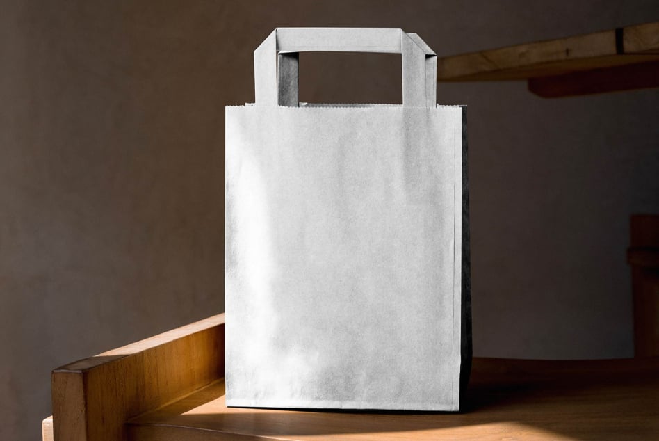 Blank white paper bag with scalloped edge trim on wooden table