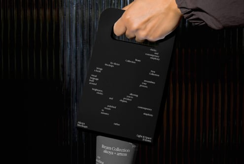 Hand gripping black clipboard with white typography scattered across surface