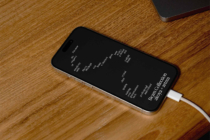 Black iPhone displaying text on dark screen with white charging cable attached