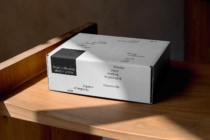 White shipping box with printed text layout on wooden surface by window