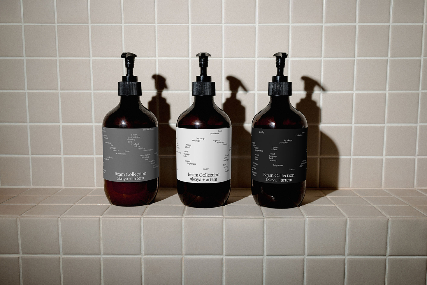 Three dark glass dispenser bottles displaying Beam Collection labels on neutral tile surface