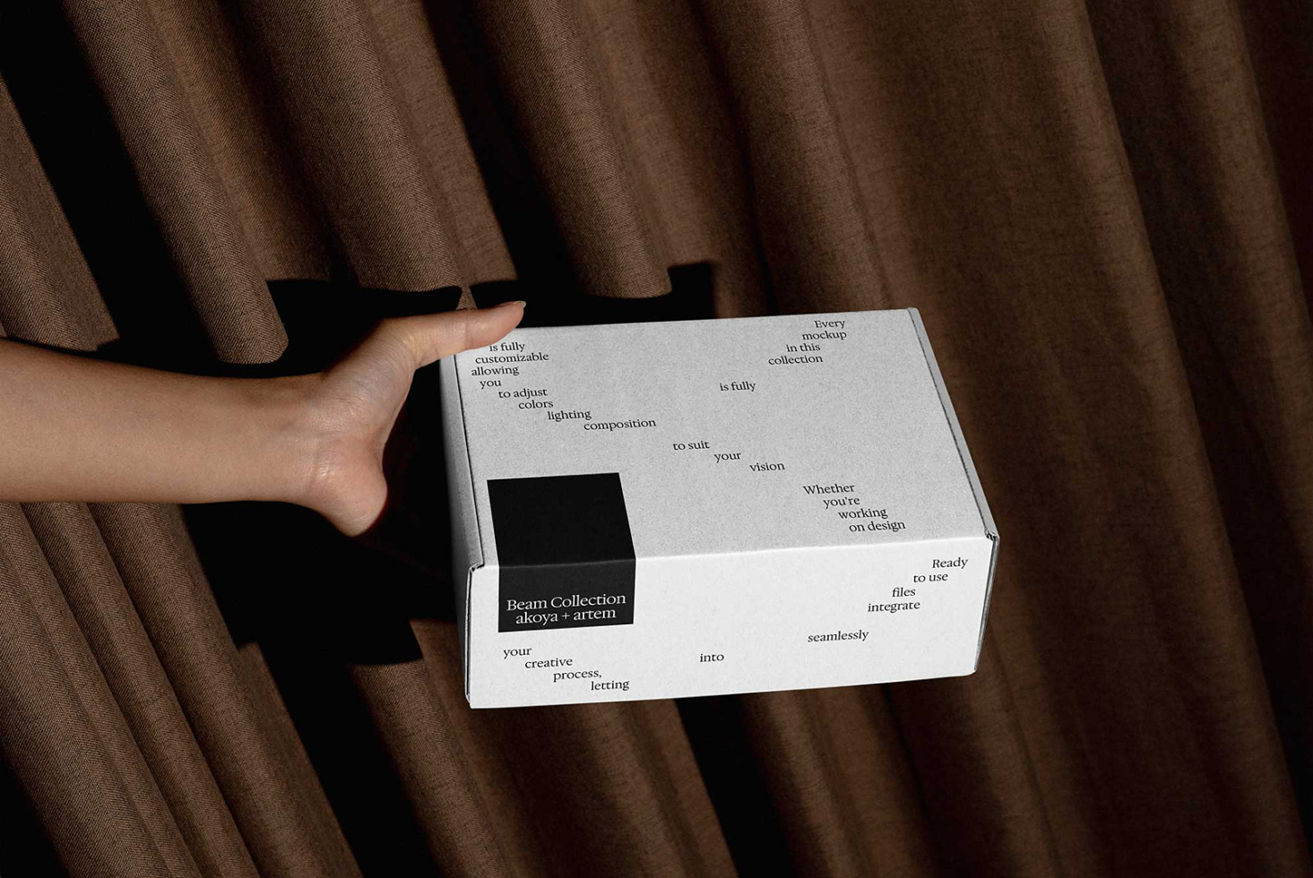 Hands holding white box with Beam Collection branding on fabric background
