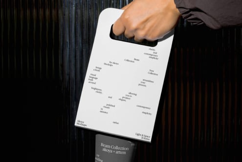 Hand holding white clipboard displaying typography layout with coffee cup below