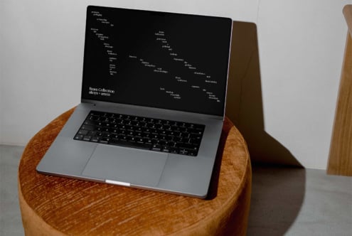 Laptop on wood table showing website design layout with black background
