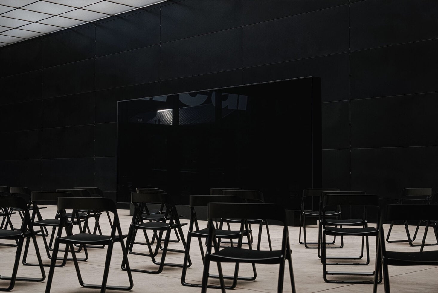 Black chairs facing empty black wall panel in modern presentation space