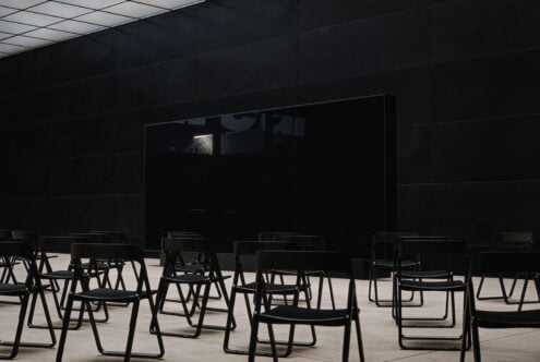 Black chairs facing empty black wall panel in modern presentation space