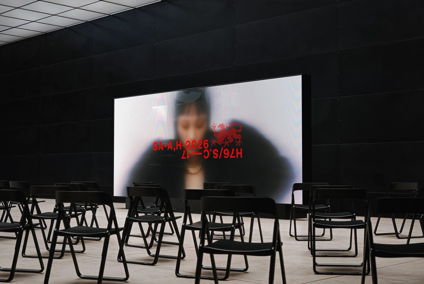 Large display screen showing blurred figure with red glitch text overlay in empty auditorium