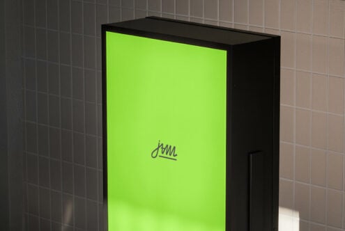 Neon green illuminated display case showing handwritten JAM signature