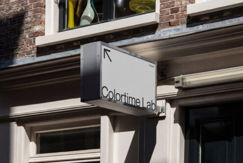 Light colored hanging shop sign with dark text on street level store entrance