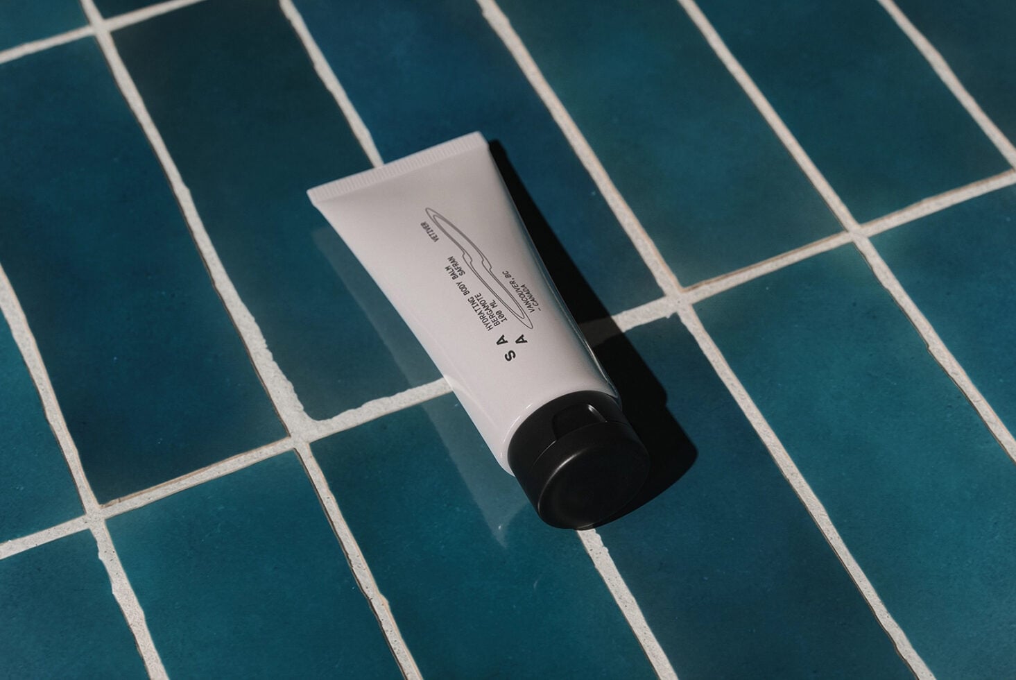 Cosmetic tube with product label text on teal grid background