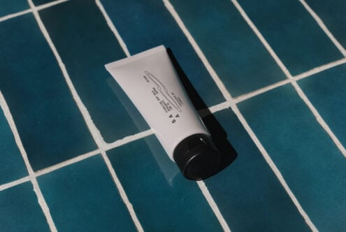 Cosmetic tube with product label text on teal grid background