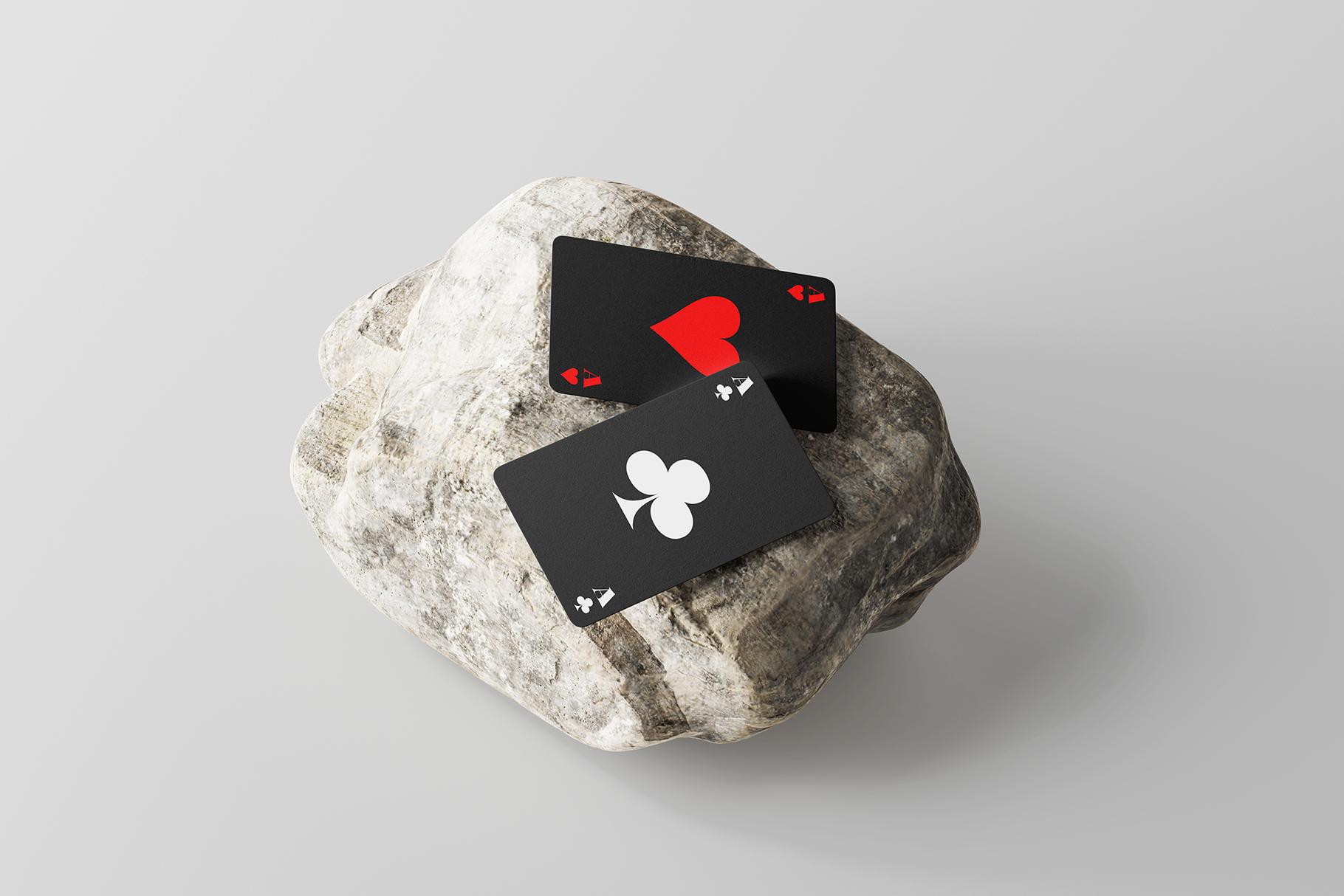 Playing cards with heart club symbols on black cards on white textured stone
