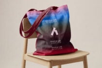 Gradient tote bag with pink to blue ombre displayed on wooden chair