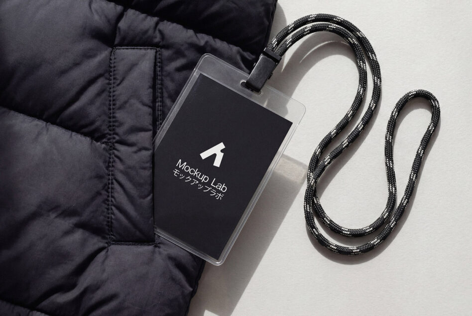 Dark ID card with white logo hanging from metallic braided lanyard on white fabric
