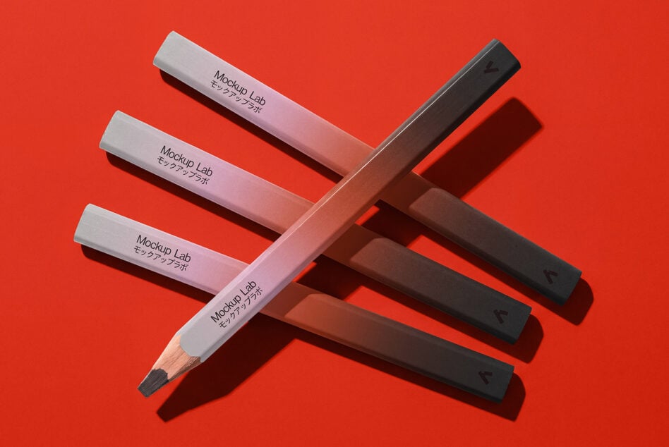 Colored pencils in white, pink, black arranged on bright red background with shadows