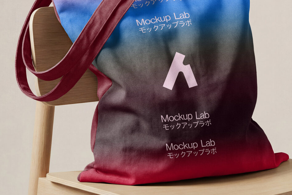 Canvas tote bag draped on wooden chair showing Mockup Lab branding in gradient colors