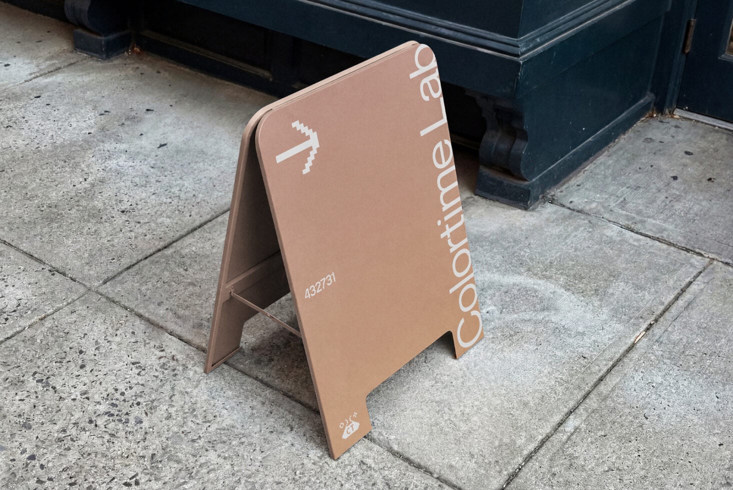 Tan colored pavement sign with Coordinate Lab logo on street