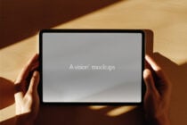 Hands holding horizontal tablet with soft gray display on wooden surface