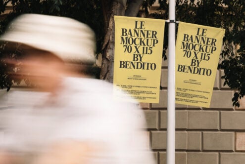 Two yellow hanging banner mockups on pole with foliage backdrop closeup