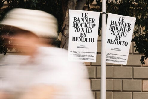 Two white hanging banner mockups on pole with foliage backdrop closeup