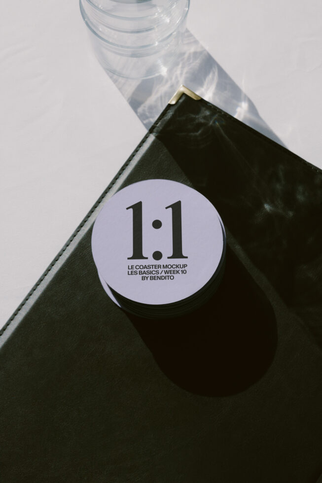 Lavender circular coaster mockup on black leather notebook with water glass