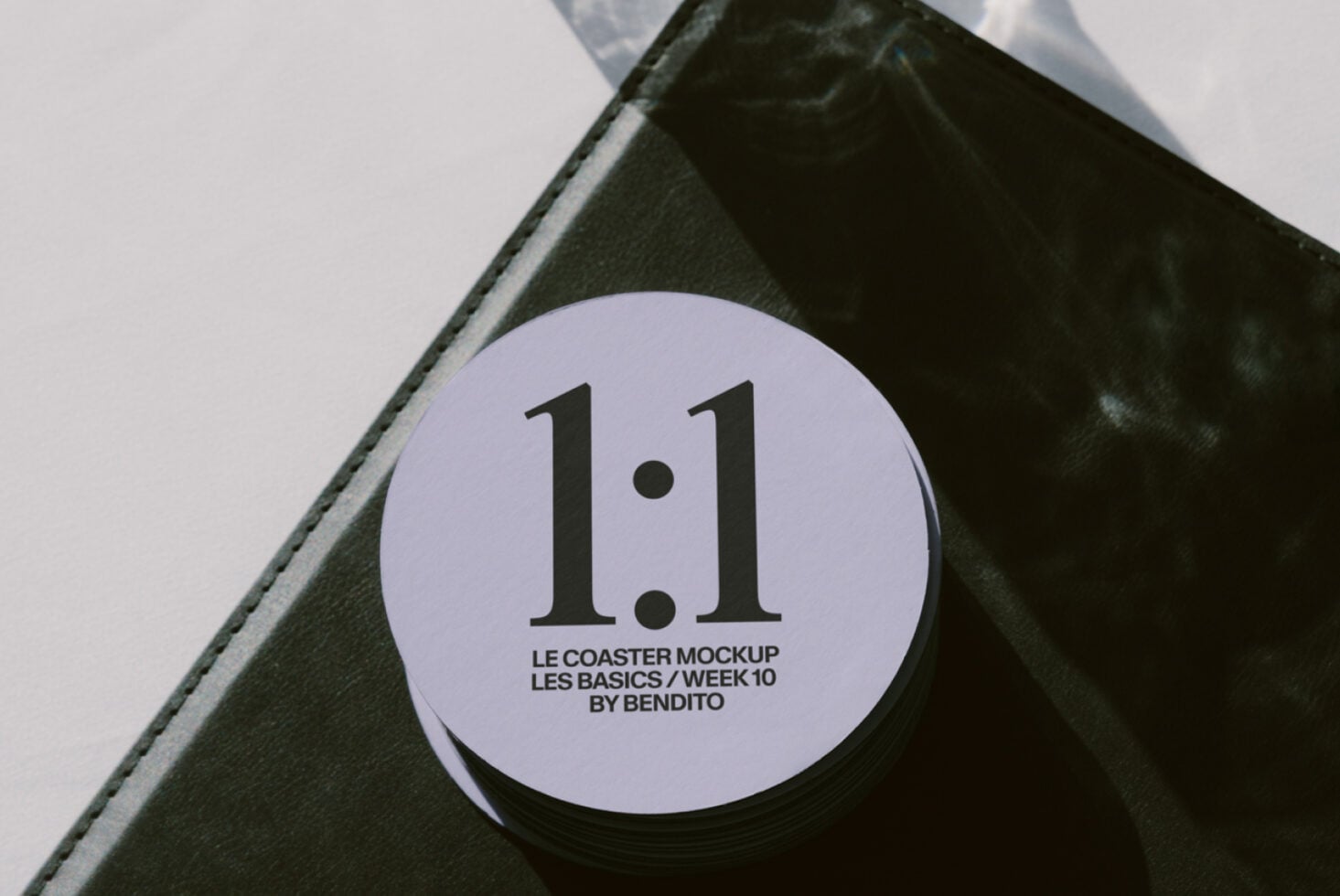 Lavender circular coaster with text on corner of black leather notebook