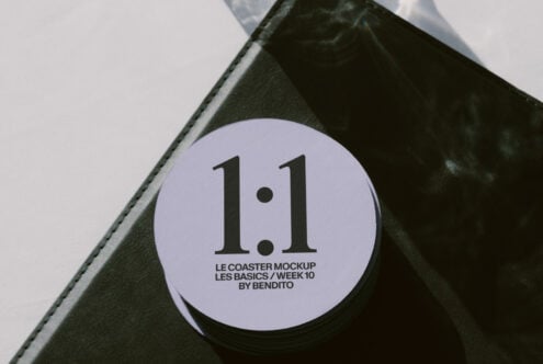 Lavender circular coaster with text on corner of black leather notebook