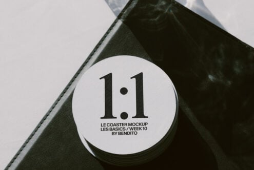 White circular coaster with text on corner of black leather notebook