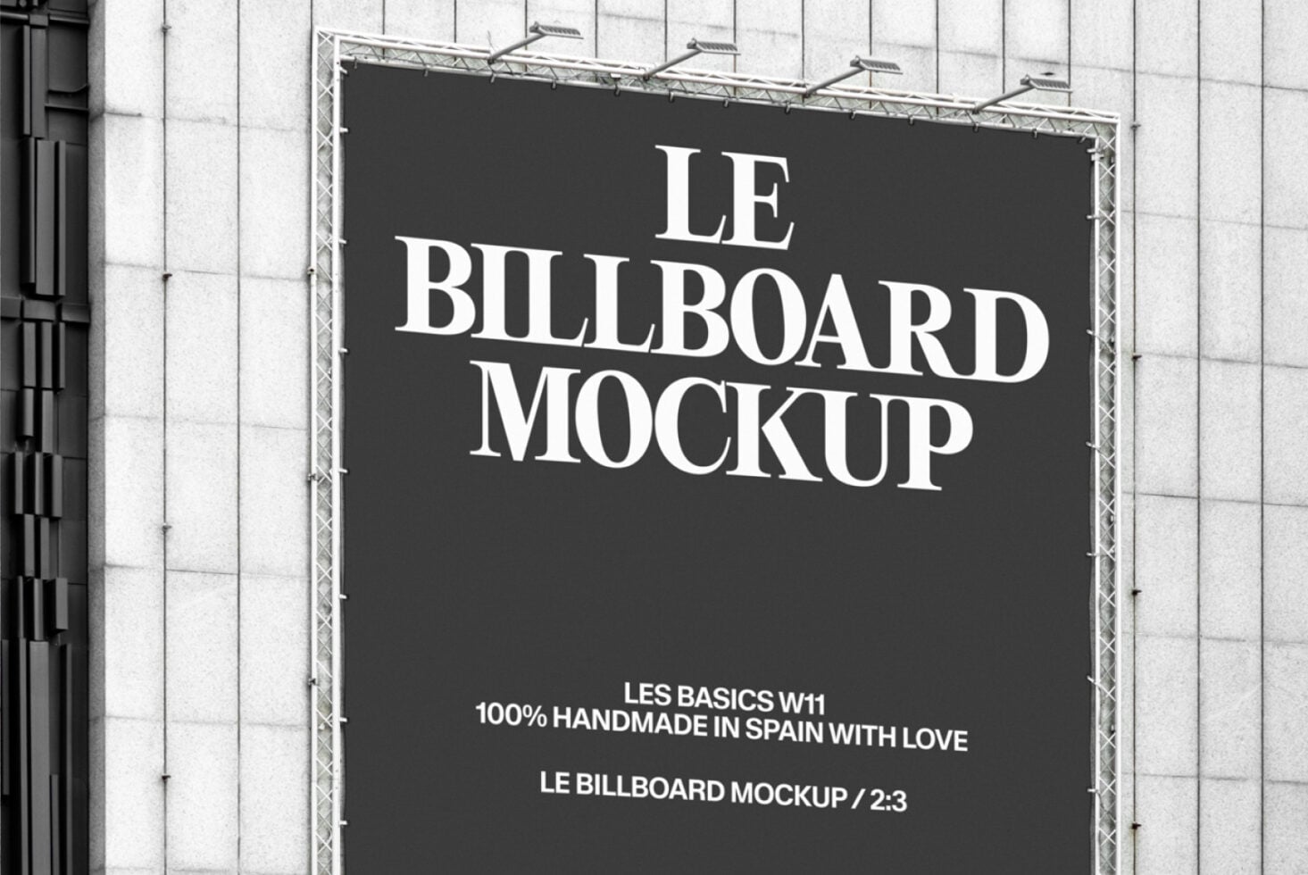 Wide shot of black billboard displaying Le Billboard Mockup text on white grid building facade