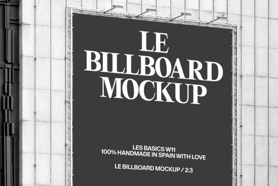 Wide shot of black billboard displaying Le Billboard Mockup text on white grid building facade