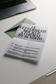 Folded letterhead with sage green envelope on desk next to laptop