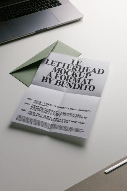 Folded letterhead with sage green envelope on desk next to laptop