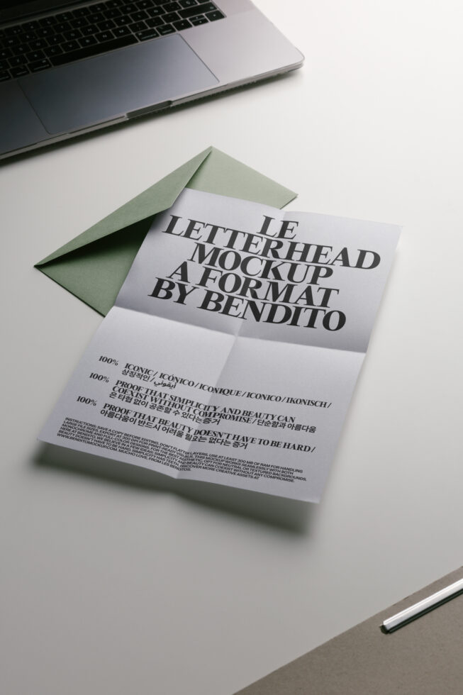 Folded letterhead with sage green envelope on desk next to laptop