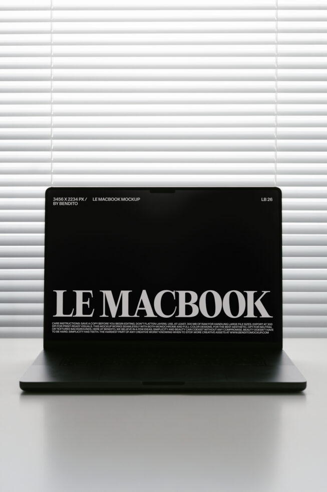 MacBook screen mockup with black background showing white serif typography against venetian blinds