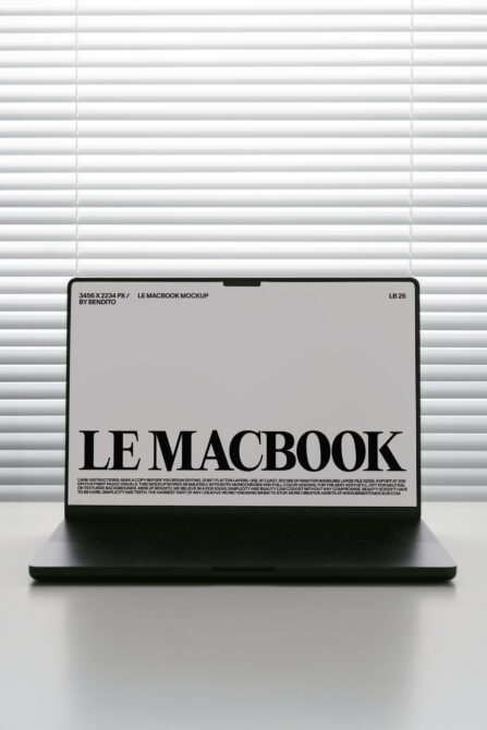 MacBook screen mockup with light gray background displaying black serif typography near window blinds