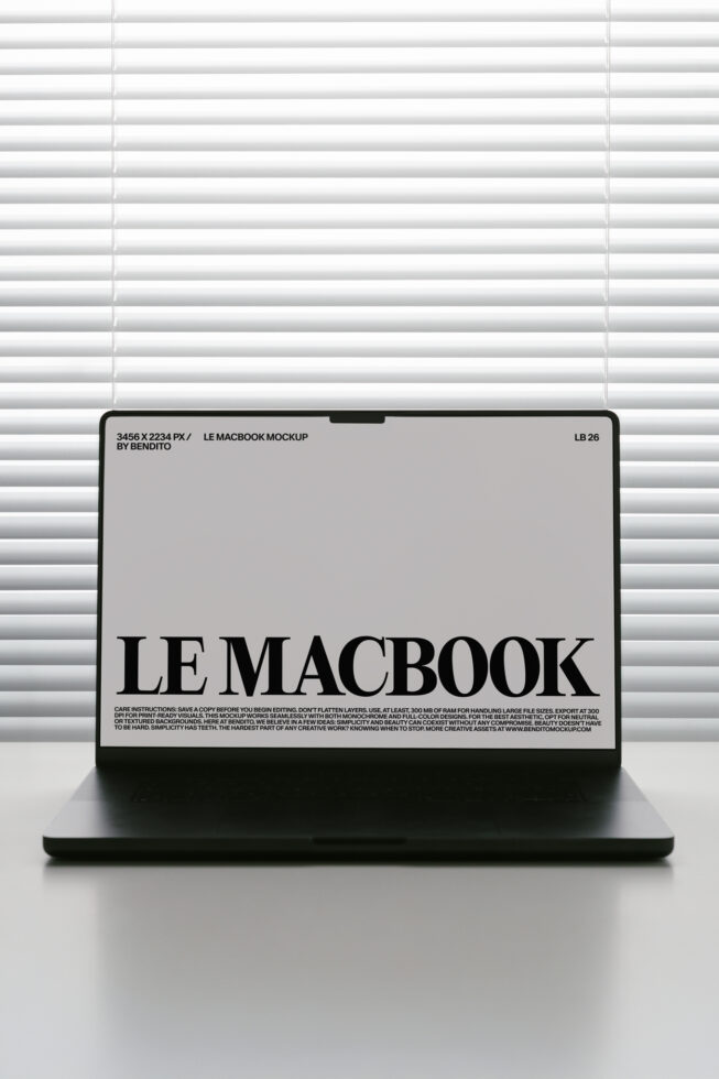 MacBook screen mockup with light gray background displaying black serif typography near window blinds