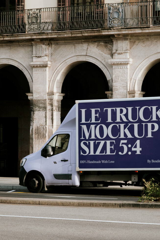 White delivery truck parked against ornate stone building with navy wrap design