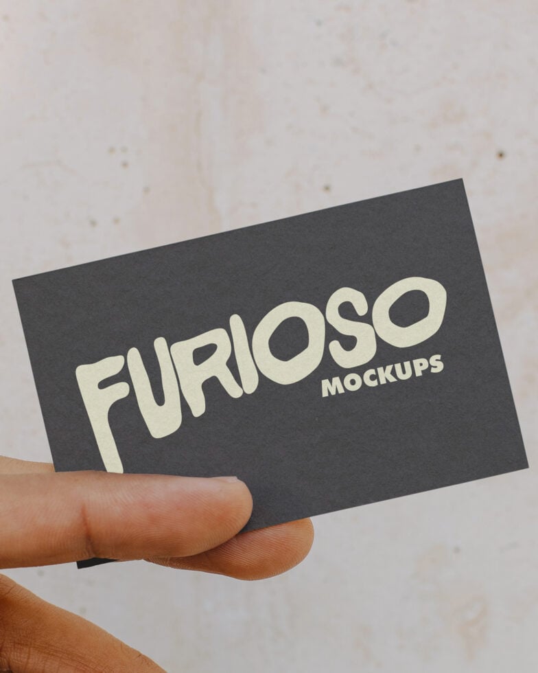 Hand holding dark business card with cream Furioso Mockups logo on textured background