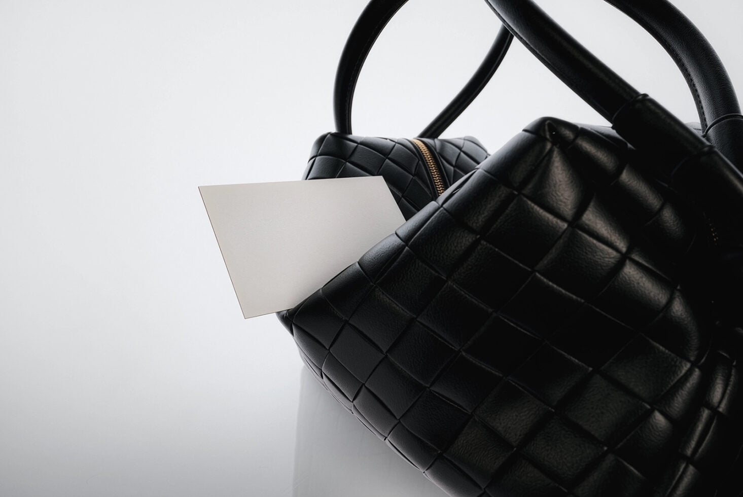 Blank white tag attached to black quilted leather handbag