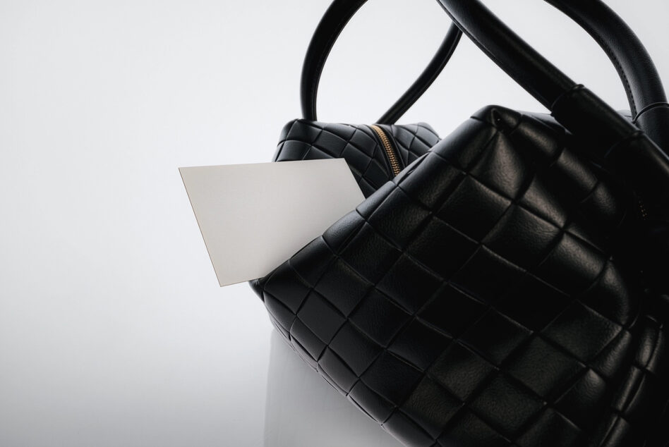 Blank white tag attached to black quilted leather handbag
