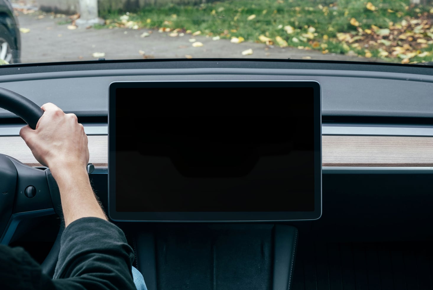Car dashboard screen with black display next to steering wheel in driver's view